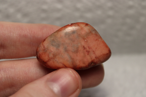 Polished orange-red stone with black and dark red veins.
